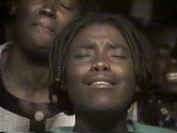 A woman praying with her eyes closed during an outreach service in Africa