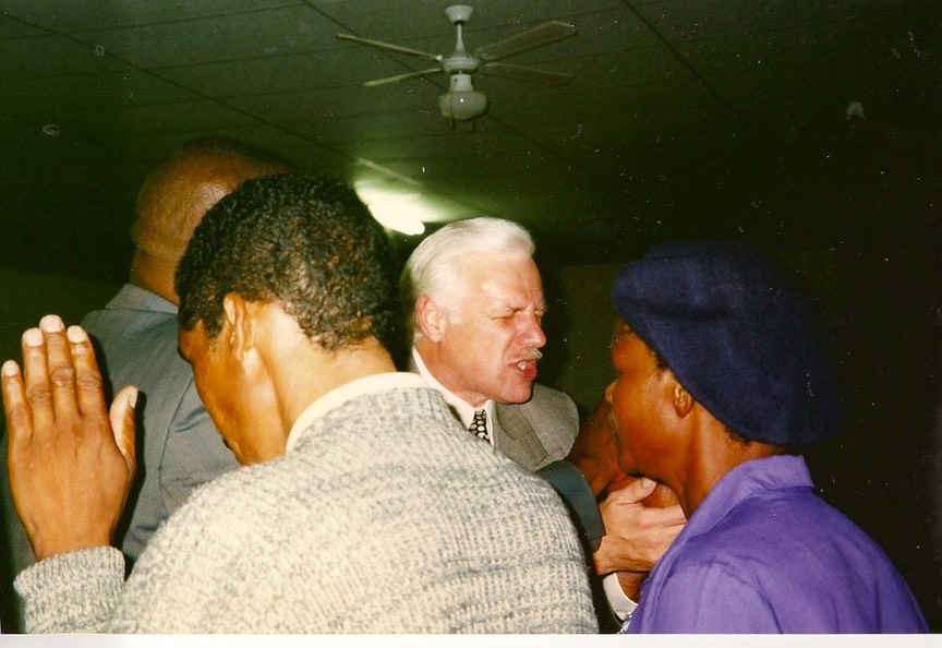 Rev. Steven A. Bach praying over people during a church service in Africa