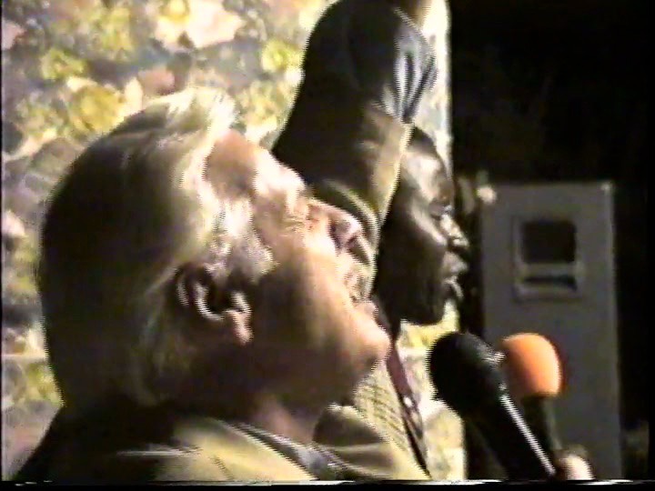Rev. Steven A. Bach preaching at an outdoor evangelistic crusade with an interpreter